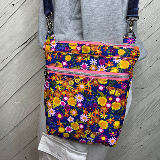 Crossbody bag with navy blue background and orange and pink flowers