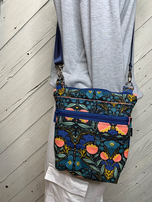 Crossbody bag with navy blue background and peach and teal flowers